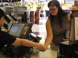 person wearing sleepshades receives change from barista